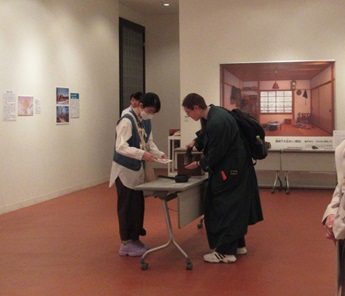 「さわってみよう！昔の道具」　錦絵に描かれたアイロンがけを説明する学生サポートスタッフ